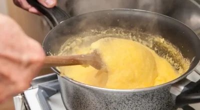 Reprodução - iStock / Imagem ilustrativa de uma pessoa fazendo polenta mole em uma panela no fogo